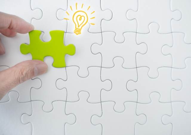 1ピースだけ緑の白いパズルと電球のイラスト