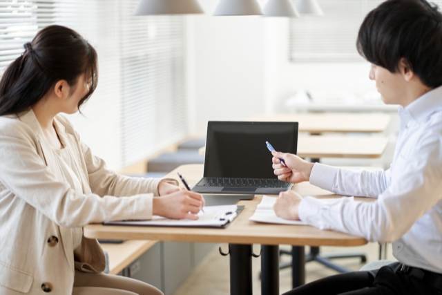 パソコンを見ながら相談している男女